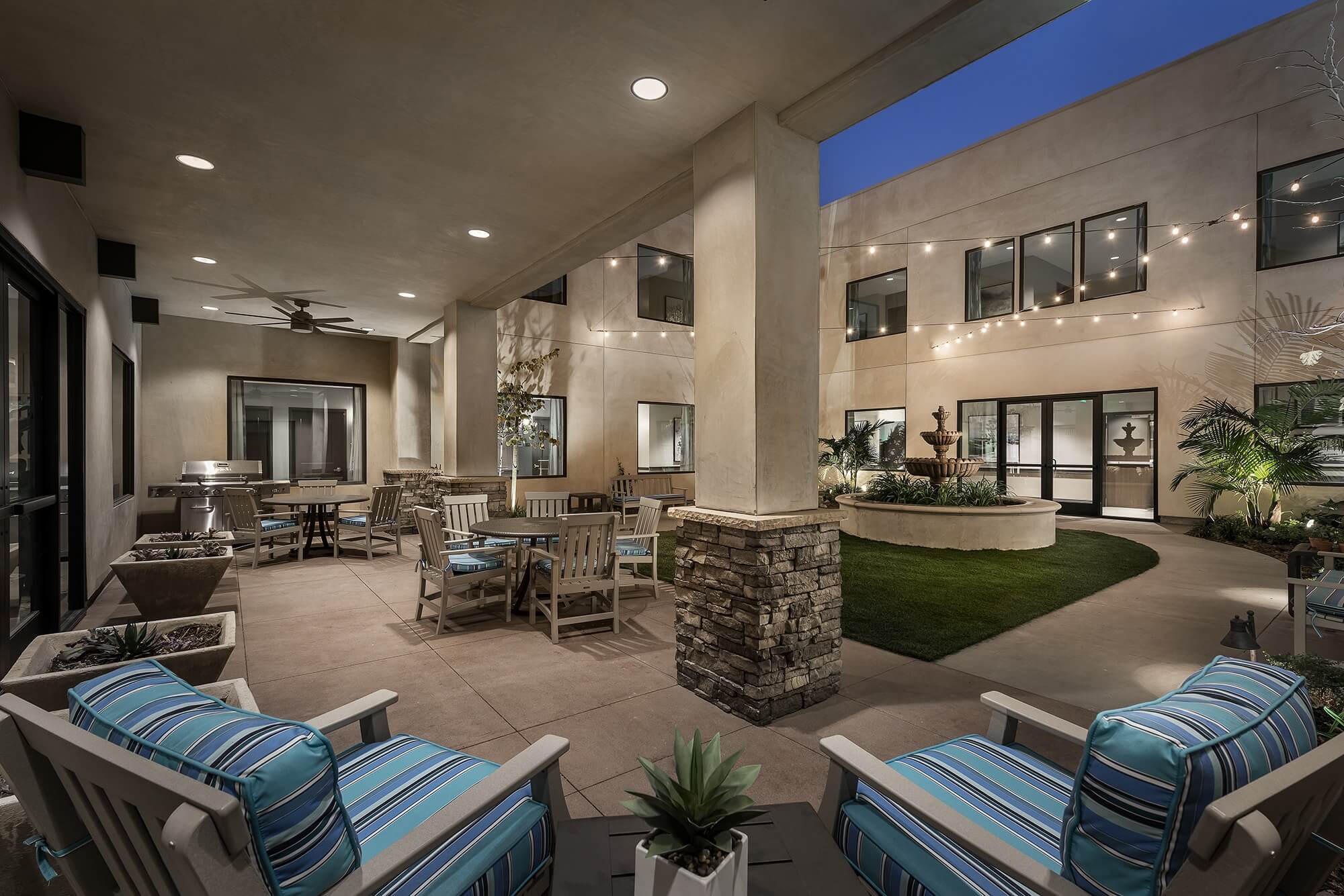 Courtyard patio during dusk, with string lights and ample outdoor seating.
