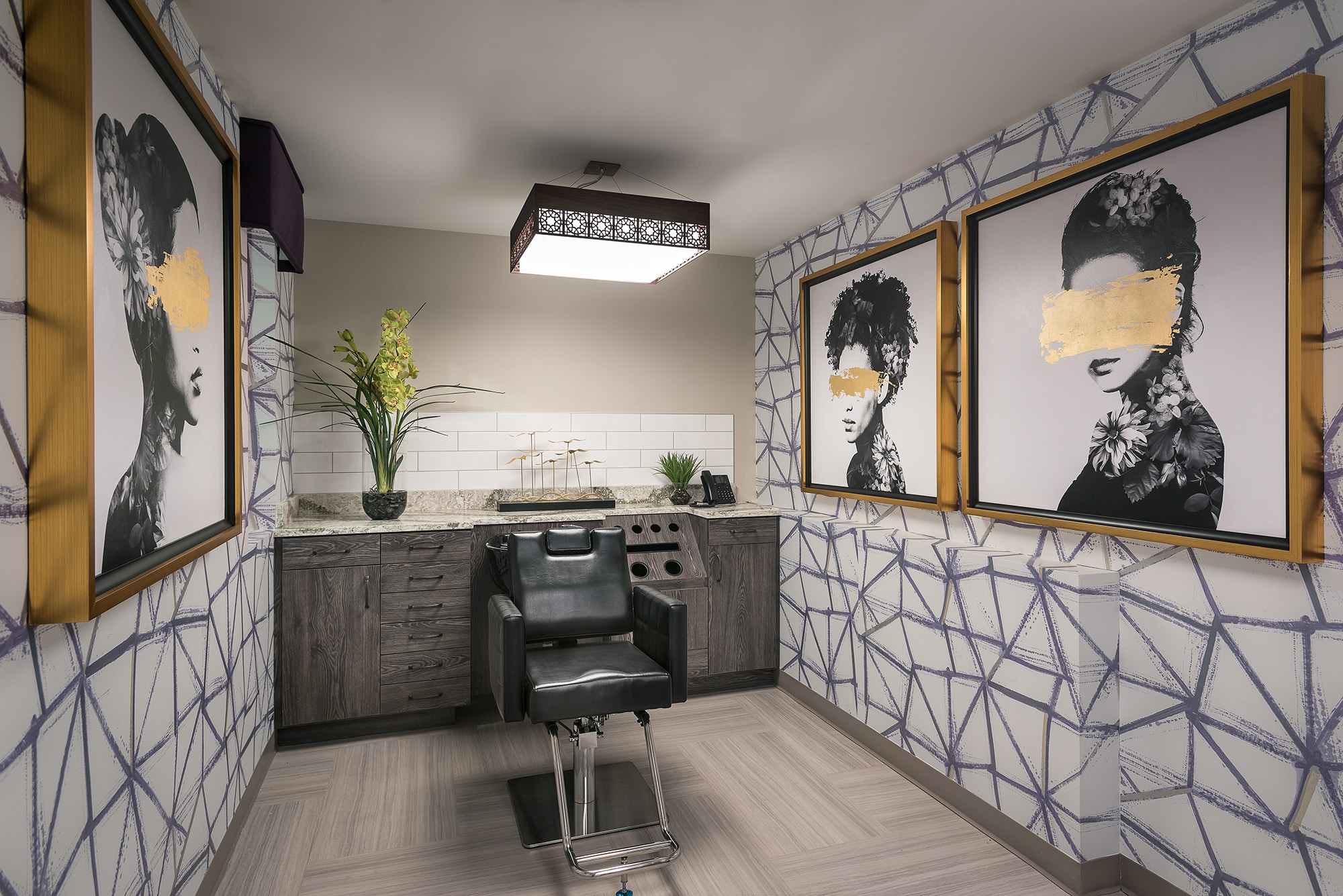 Modern salon set up with salon chair, large portrait paintings, and counter.