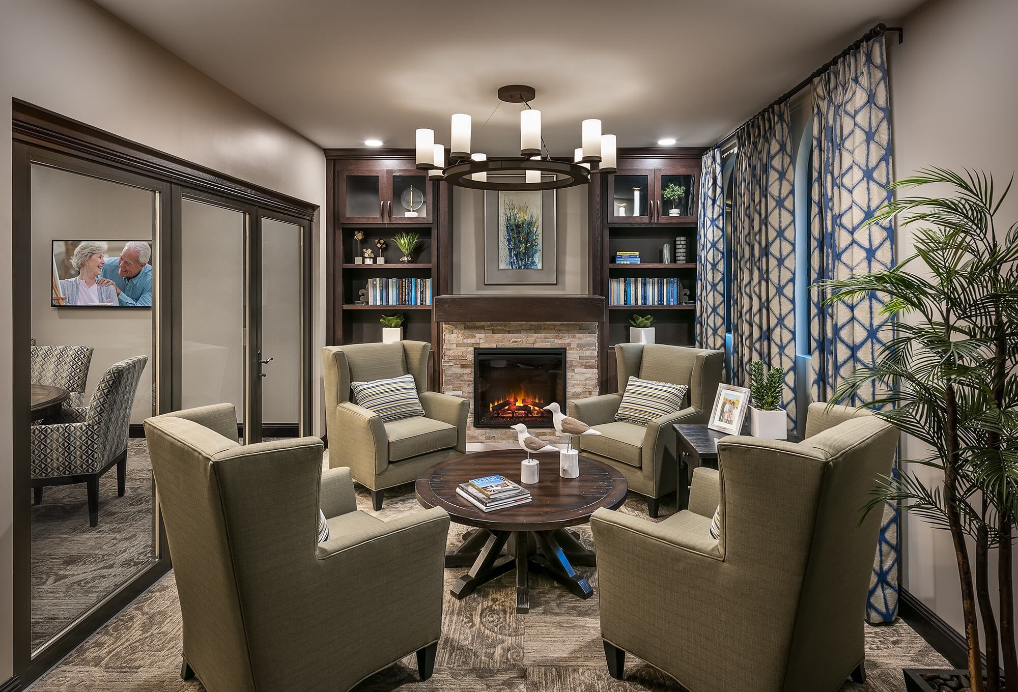 Cozy seating area around fireplace and bookcase, featuring four armchairs around a coffee table.
